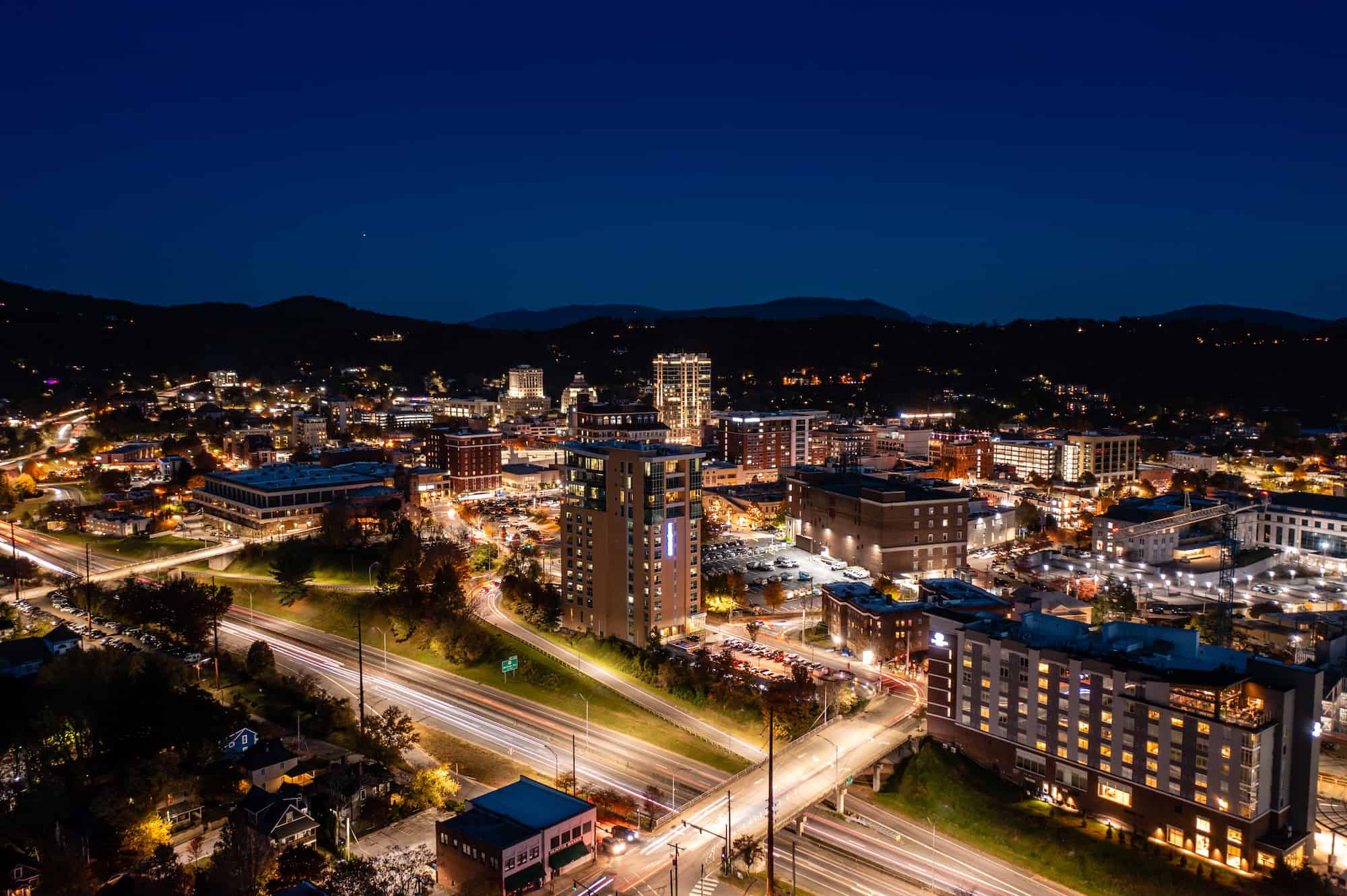 Street view of downtown Asheville with shops and cars driving